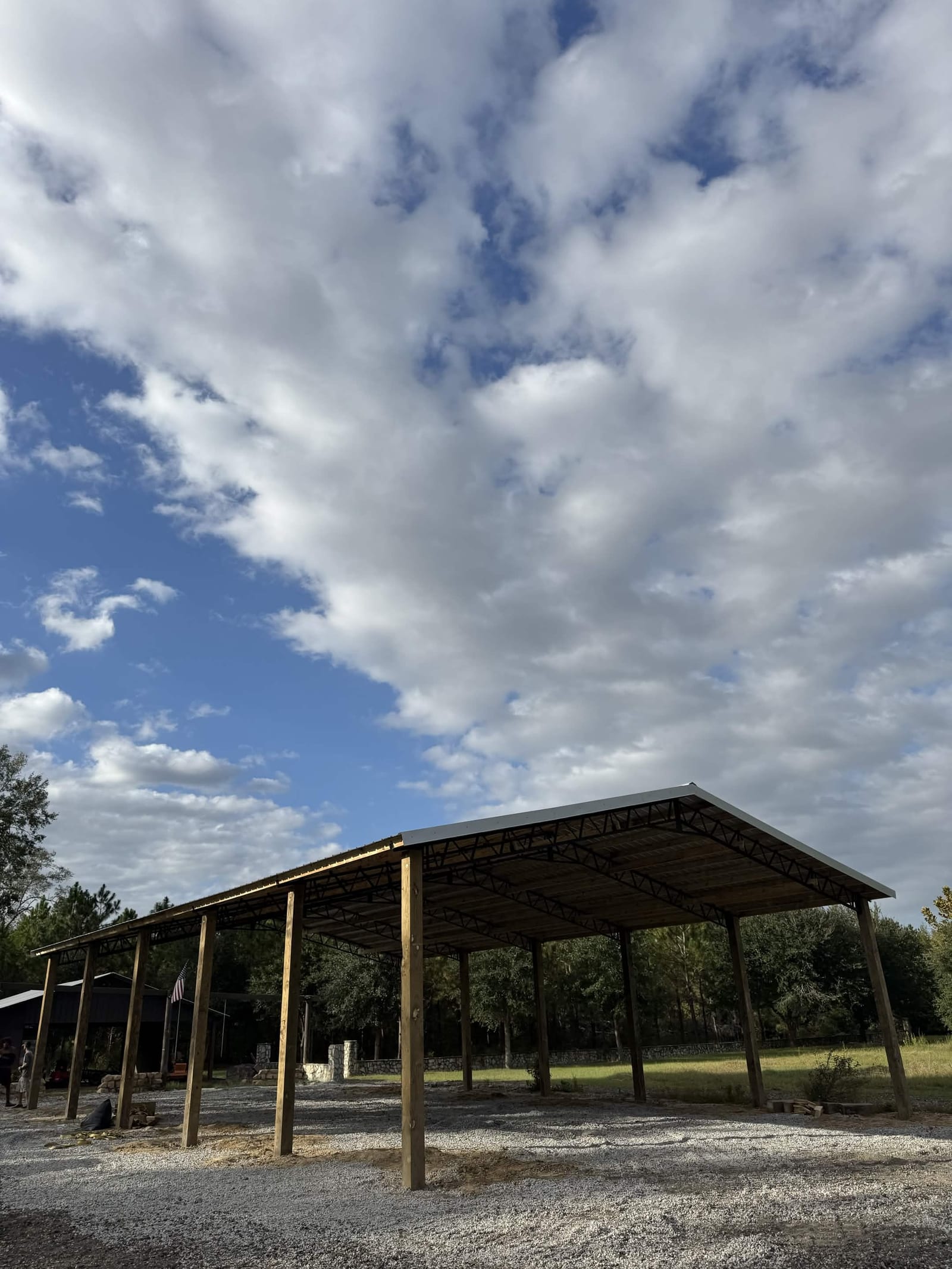 Open-sided pole barn with metal roof under dramatic sky