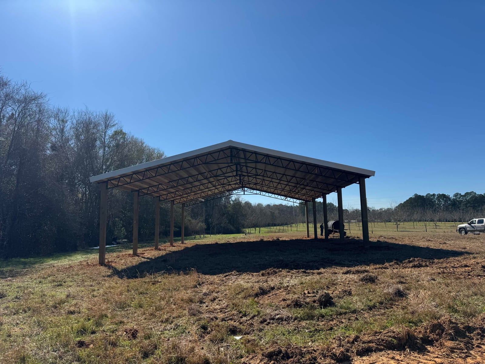 Completed pole barn on open pastureland backlit by the sun