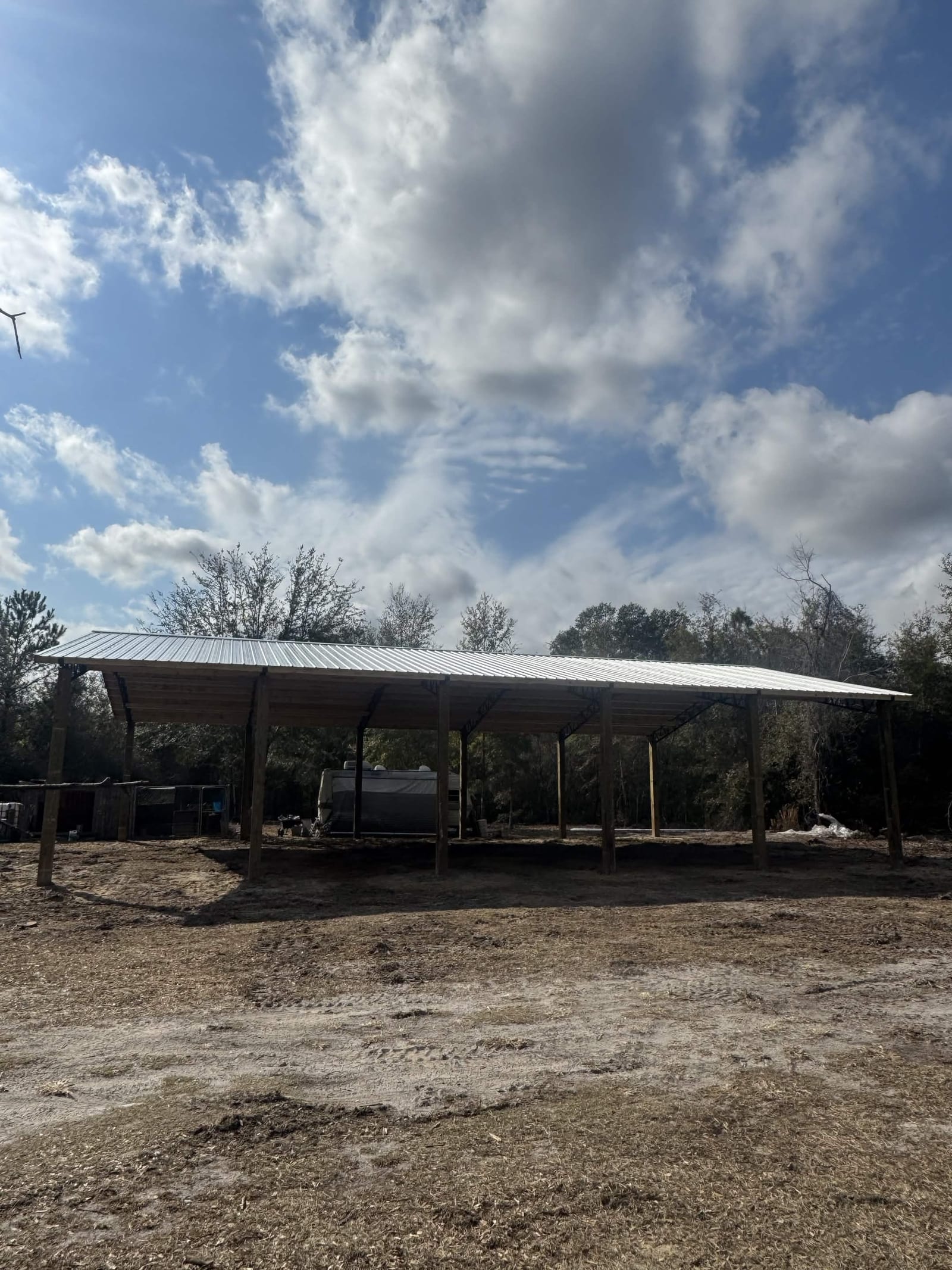 Pole barn with lean-to extension on a rural Florida property with cloudy sky